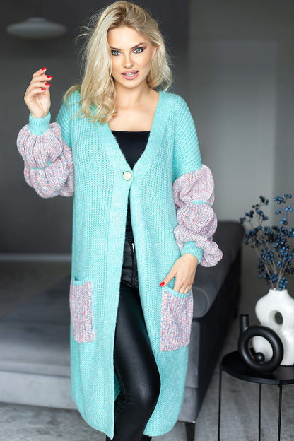 Elegant oversized cardigan in a vibrant aqua hue, adorned with plush puff sleeves and pocket details, perfectly complemented by sleek black leggings, captured in a modern living space.