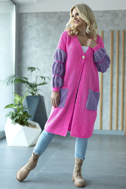 Vibrant pink long sleeve cardigan featuring plush balloon sleeves and contrasting pocket details, styled with casual denim and boots in a chic environment.