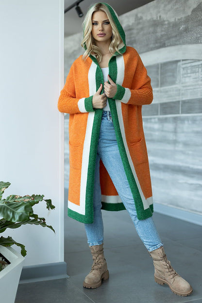 Luxury soft fluffy cardigan with a hood and slip pockets in vibrant orange and green colours, modelled by a woman in casual jeans and boots, set against a modern interior backdrop.