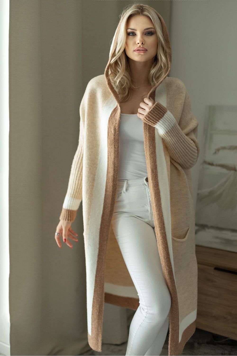 Elegant luxury loose cardigan with hood in soft fluffy fabric, featuring slip pockets, worn by a model against a stylish interior backdrop.