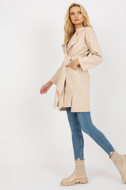 Elegant side view of a women's slim fit beige coat by Och Bella, showcasing a flattering silhouette with a tie belt and versatile patch pockets, ideal for sophisticated autumn outfits.