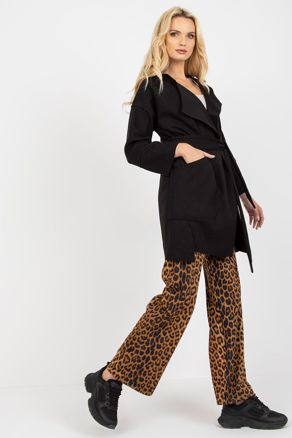 Stylish side view of a woman showcasing a black slim fit coat tied at the waist, adorned with spacious patch pockets and contrasting leopard print pants.