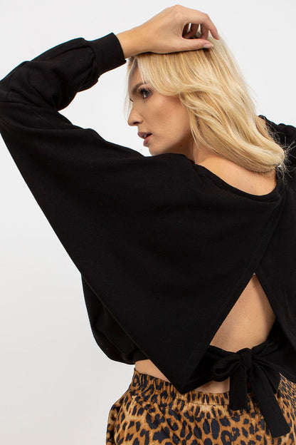 Chic women's black sweater showcasing a unique back design with a tied detail, complemented by trendy leopard print pants.