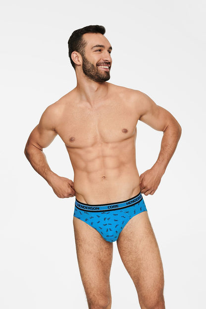 Elegant male model showcasing Henderson Boost Comfort Briefs in a vibrant blue featuring a stylish motorcycle print, complemented by a black elastic waistband with the Henderson logo.