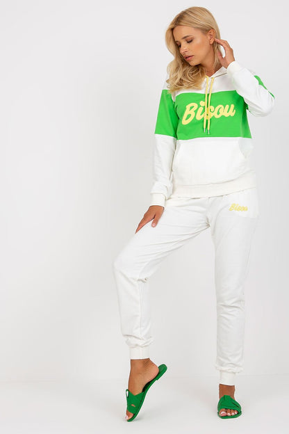 Sophisticated woman showcasing a stylish cotton blend hoodie and sweatpants set in white and green, designed with decorative patch details, accented by matching green sandals.