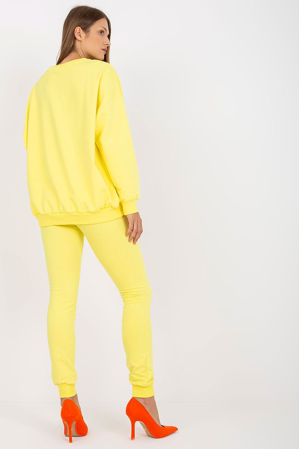 Chic yellow cotton-spandex sweatsuit set featuring a loose-cut sweatshirt and fitted long pants, paired with striking orange stiletto heels, ideal for a stylish casual look.