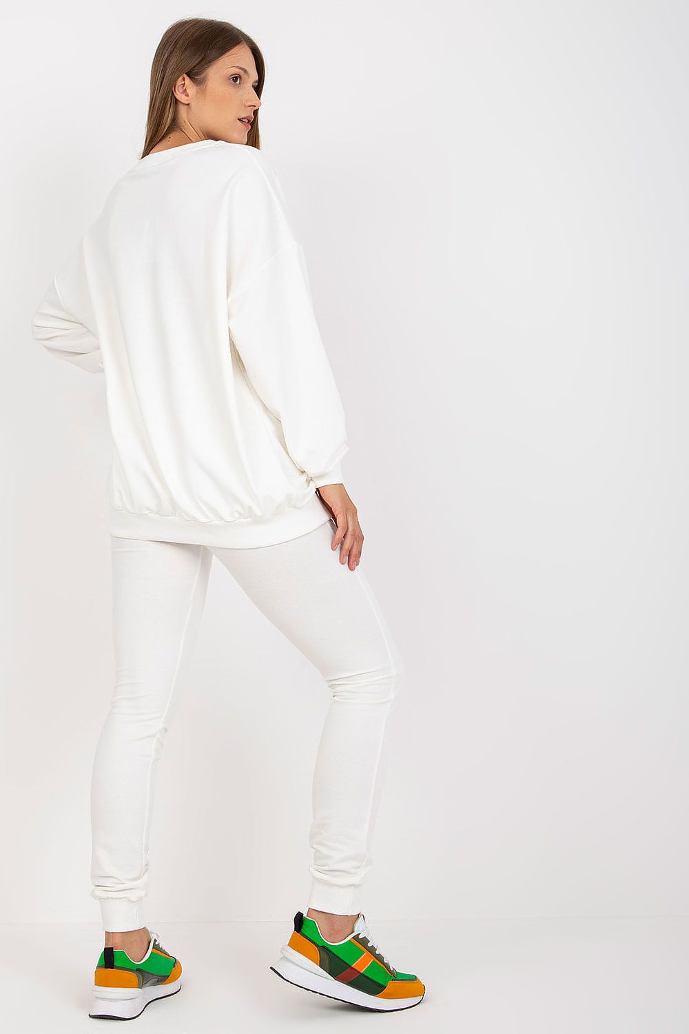 Contemporary white sweatsuit featuring a plush loose-cut sweatshirt and sleek long pants, complemented with eye-catching trainers, exuding luxury and comfort.