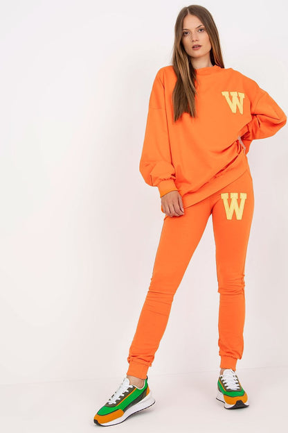Vibrant orange sweatsuit set with relaxed sweatshirt and fitted trousers, accentuated by luxurious details and stylish trainers, perfect for a chic casual ensemble.