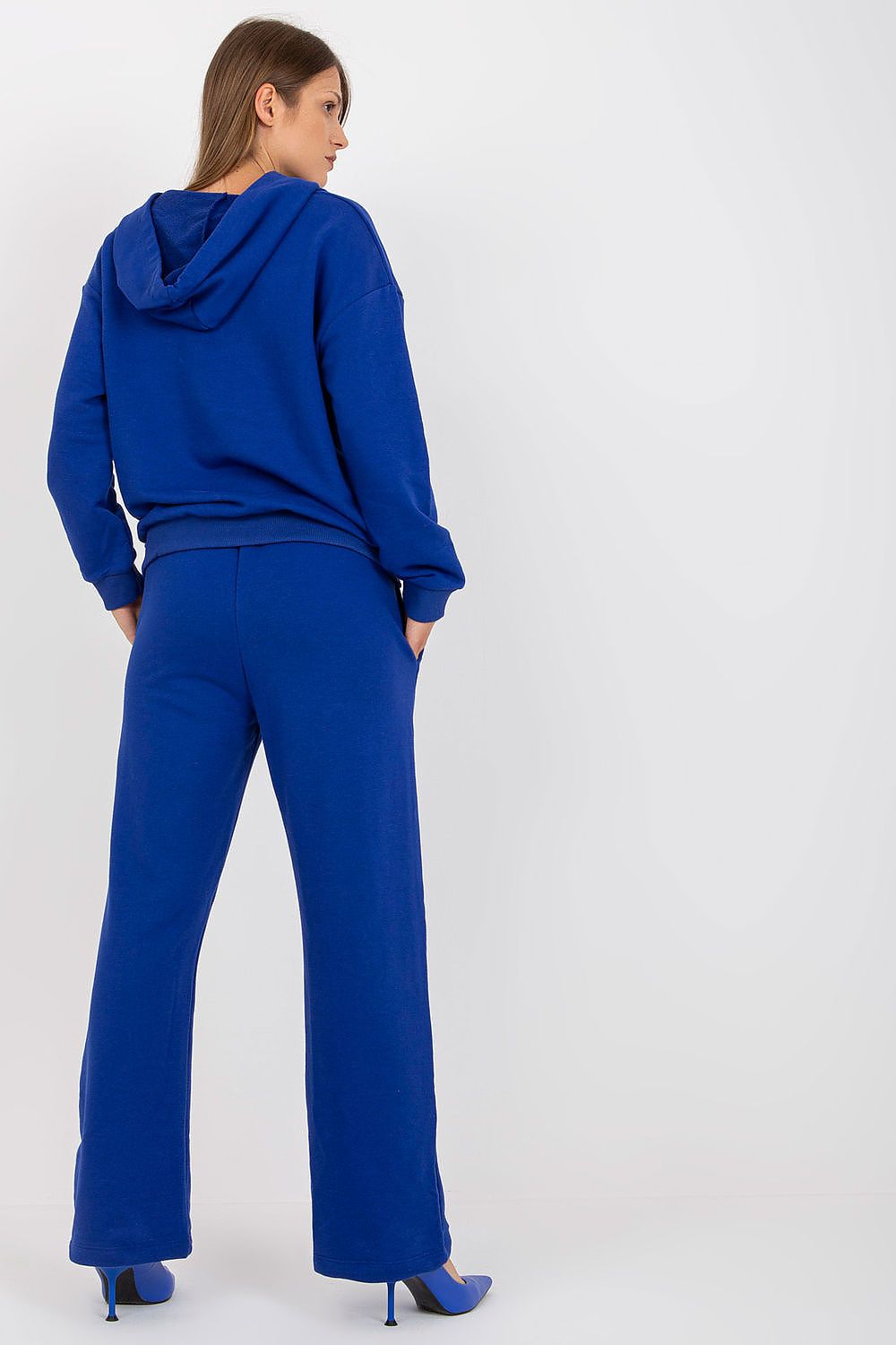 Stylish back view of a women's luxury cotton hoodie sweatshirt set in blue, highlighting relaxed fit and comfort, paired with elegant heels.