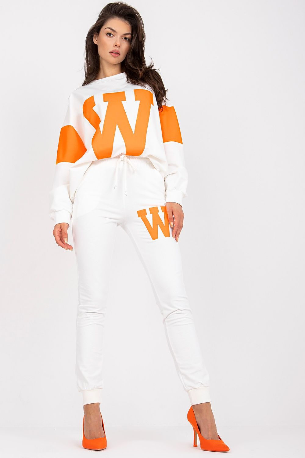 Elegant women's casual wear, highlighting a loose sweatshirt adorned with a prominent 'W' design, paired with tailored white pants and orange heels, exuding sophistication and comfort.