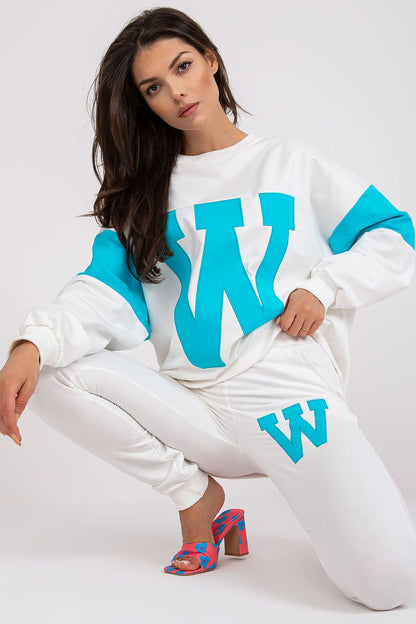 Chic women's tracksuit set showcasing a white sweatshirt with striking aqua accents and tailored pants, complemented by fashionable heels, perfect for upscale athleisure.