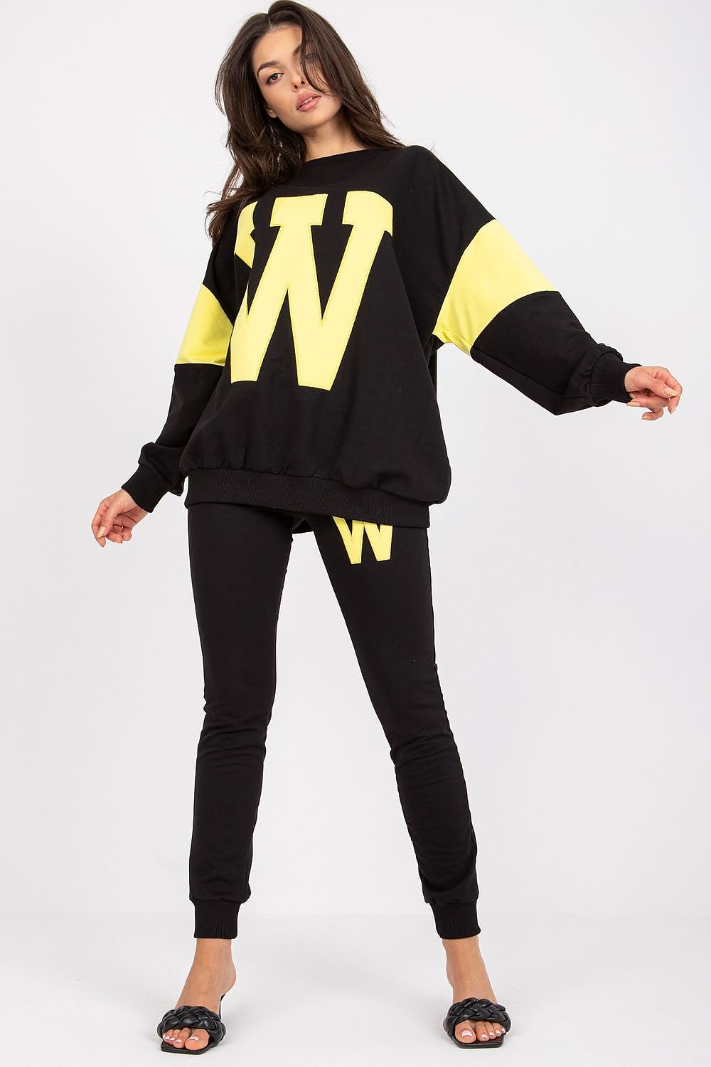 Sophisticated women's tracksuit set in black with bright yellow accents, designed with a loose sweatshirt and tailored pants, ideal for a stylish streetwear appearance.