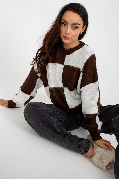 Luxurious women's long-sleeve acrylic sweater in brown and white check pattern, styled elegantly while seated on the floor, exuding casual sophistication.