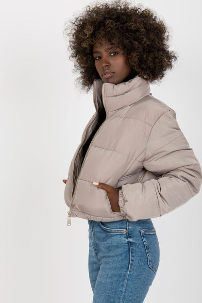 Chic short quilted jacket in beige with a contemporary design, showcasing a model in a stylish pose, perfect for luxury winter fashion.