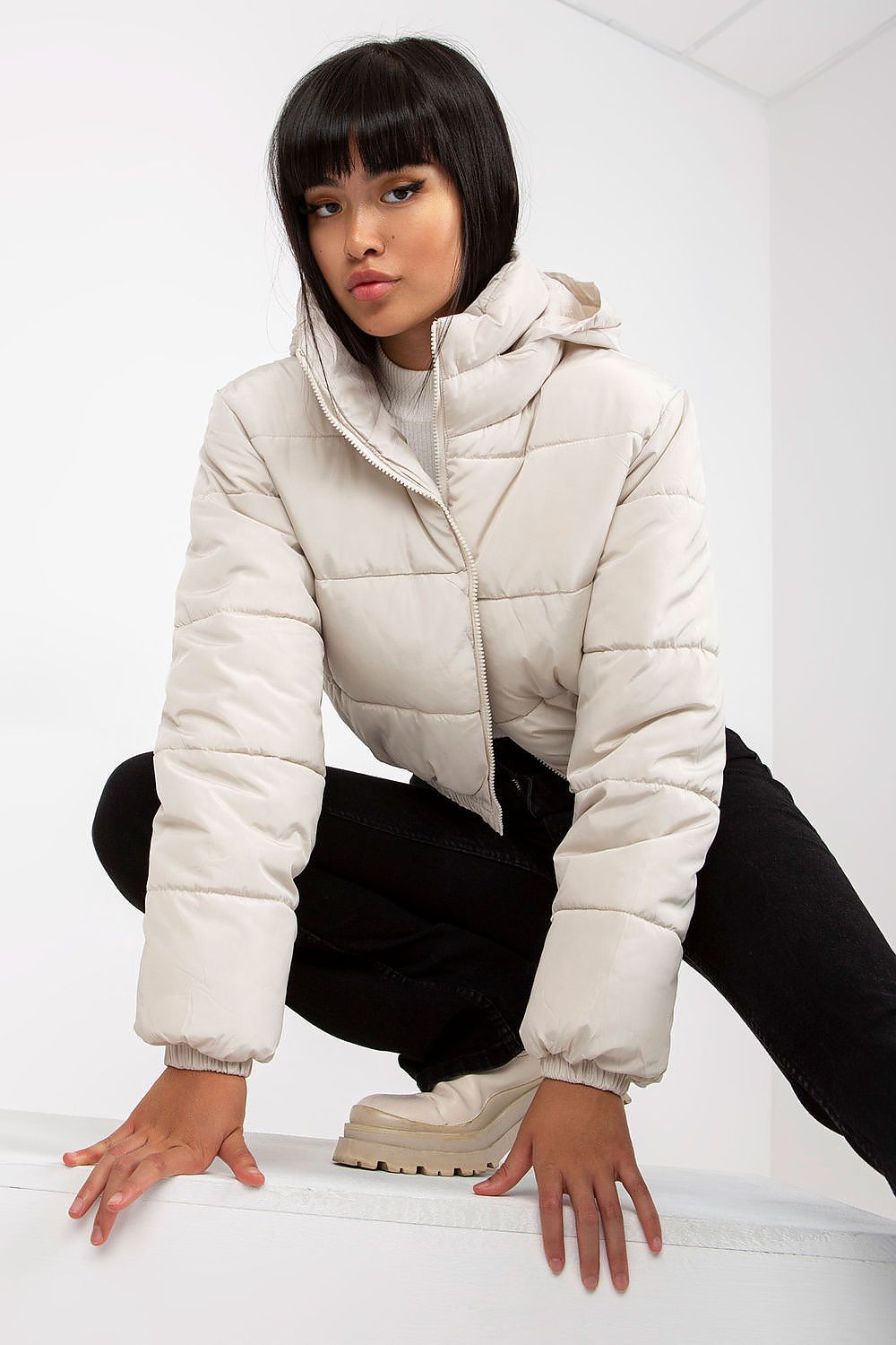 Stylish model showcasing a light beige quilted jacket with a hood, complementing a luxurious winter ensemble with a contemporary edge.