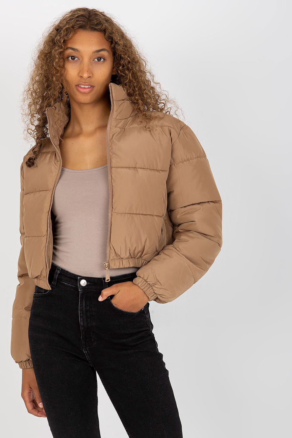 Elegant model displaying a sumptuous brown quilted jacket with a zipper closure, styled with a fitted top and black high-waist jeans, radiating modern luxury.
