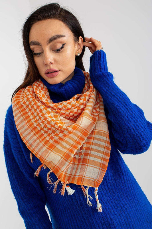 Luxurious checkered neckerchief scarf in vibrant orange and cream, styled elegantly with a cozy blue sweater, offering a chic and fashionable look.