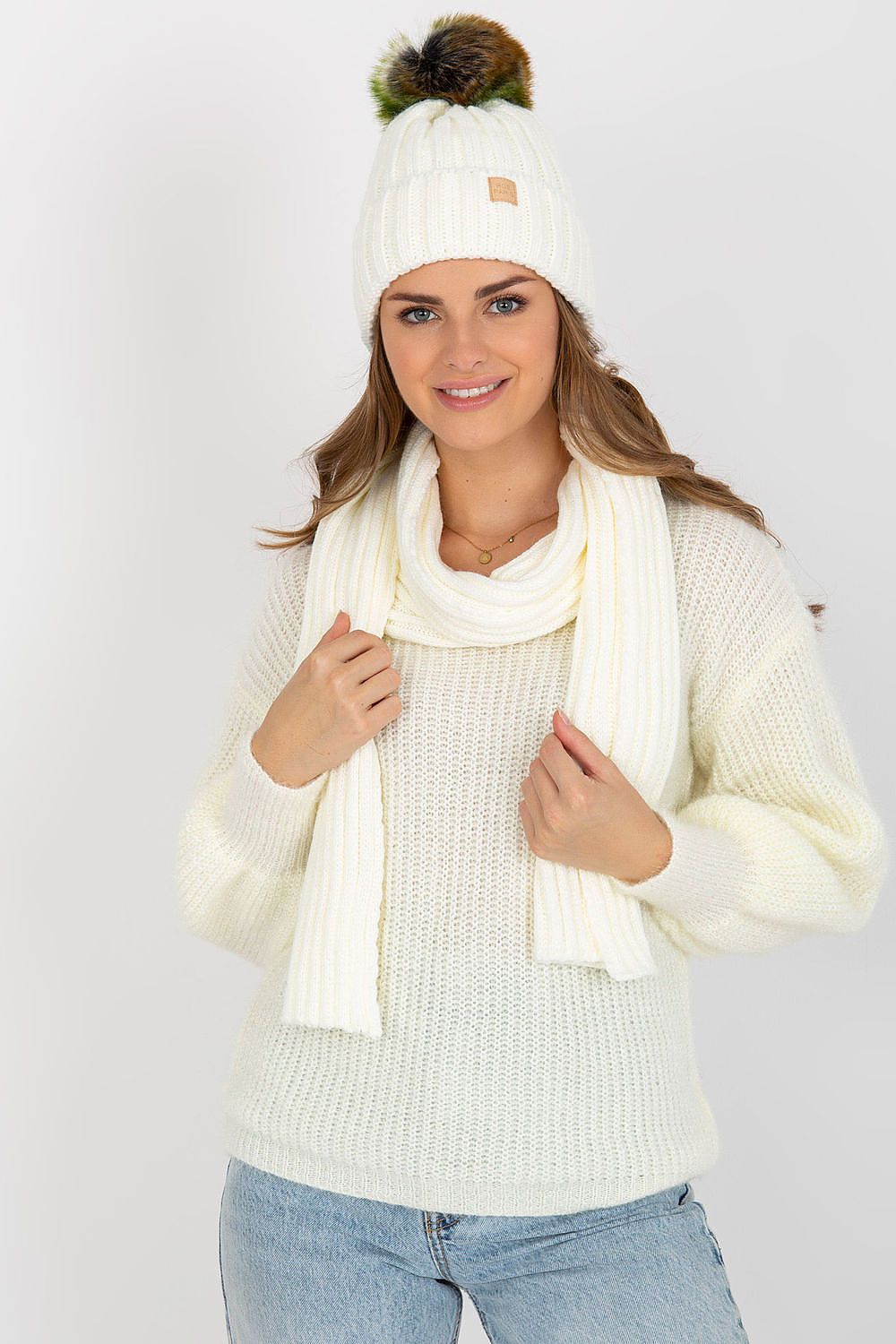 Elegant woman wearing a stylish cream winter hat and matching scarf set, exuding luxury in a soft knitted design, complemented by her cozy cable knit sweater.