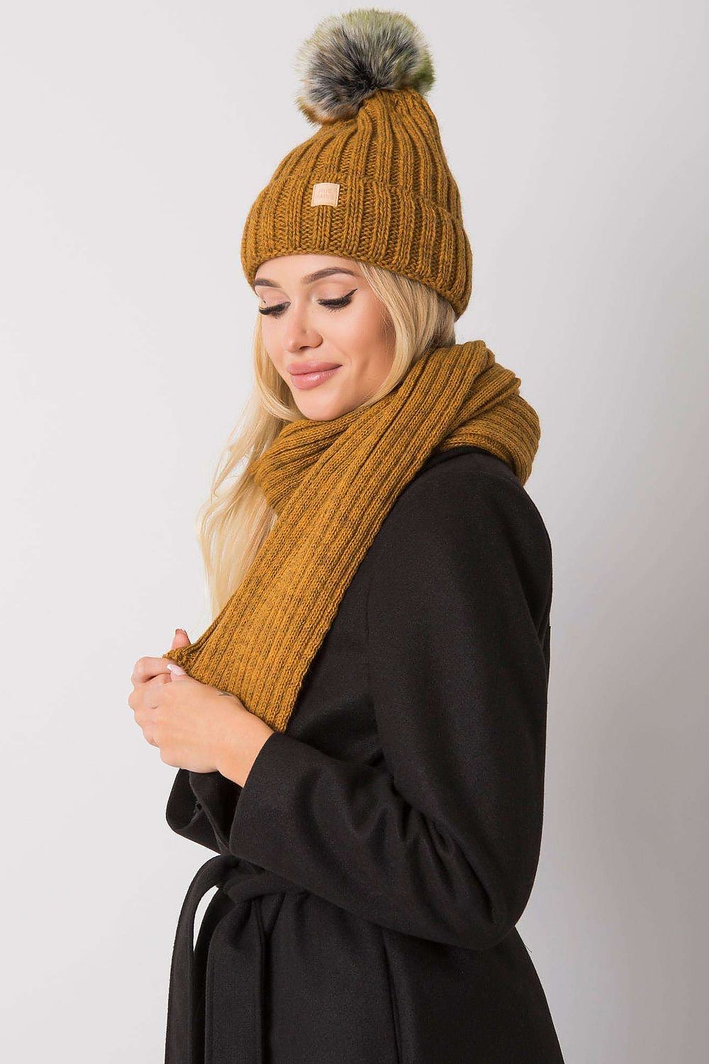 Side angle of a beautiful model in a mustard winter hat and scarf ensemble, showcasing a rich texture and warmth suitable for upscale winter fashion.
