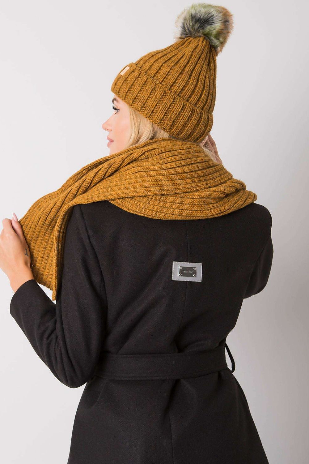 Elegant woman showcasing a stylish mustard winter hat and scarf set, perfect for luxury winter fashion.
