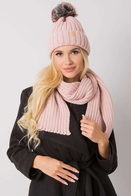 Chic model wearing a soft pink winter hat with pom-pom and matching scarf, embodying luxury winter accessories.