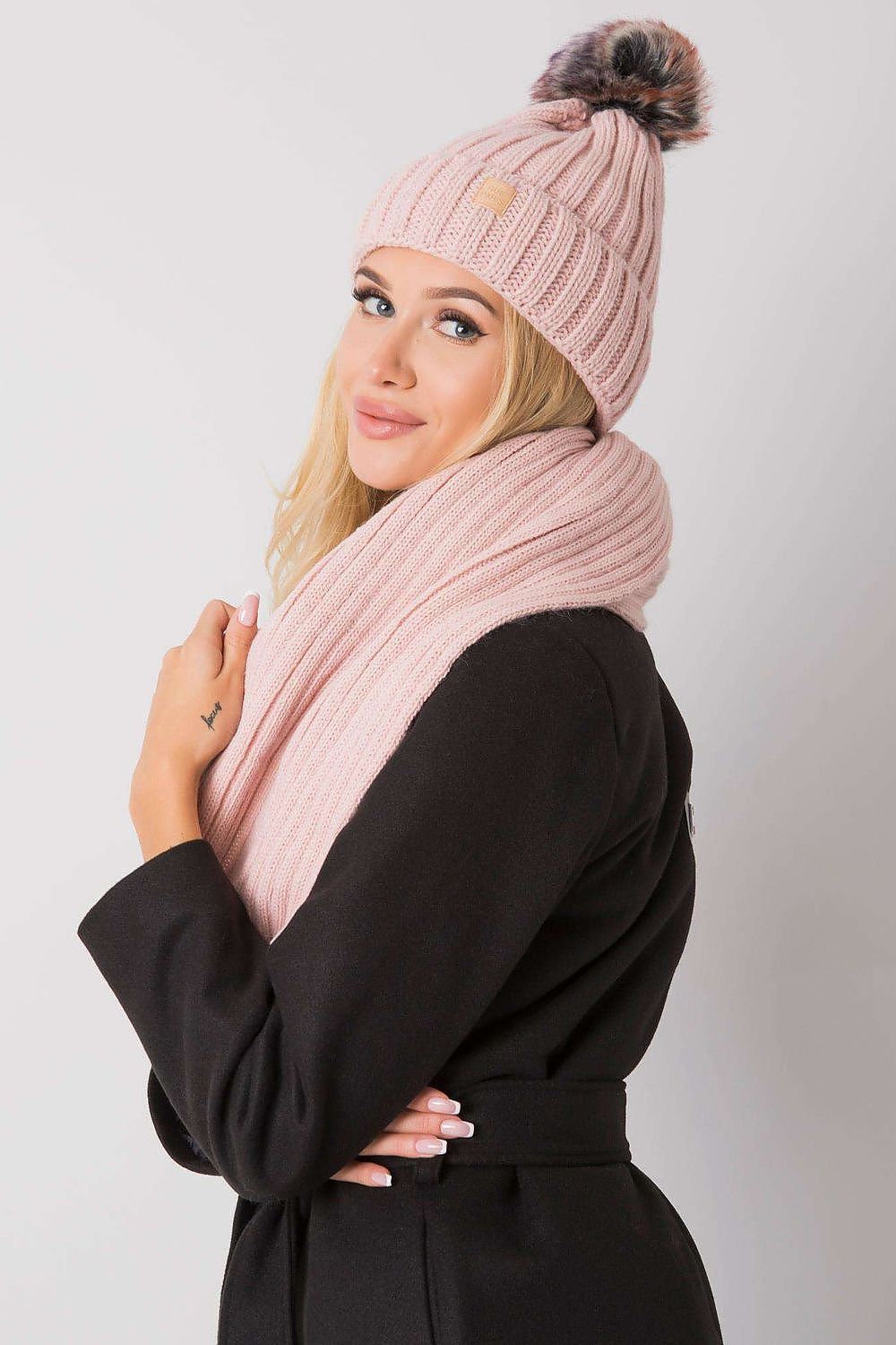 Sophisticated close-up of a woman in a pink ribbed winter hat and scarf set, ideal for upscale winter style.