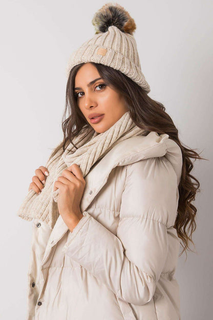 Elegant winter hat and scarf set styled with a plush pom pom, modelled by a woman in a chic coat for luxurious cold weather fashion.