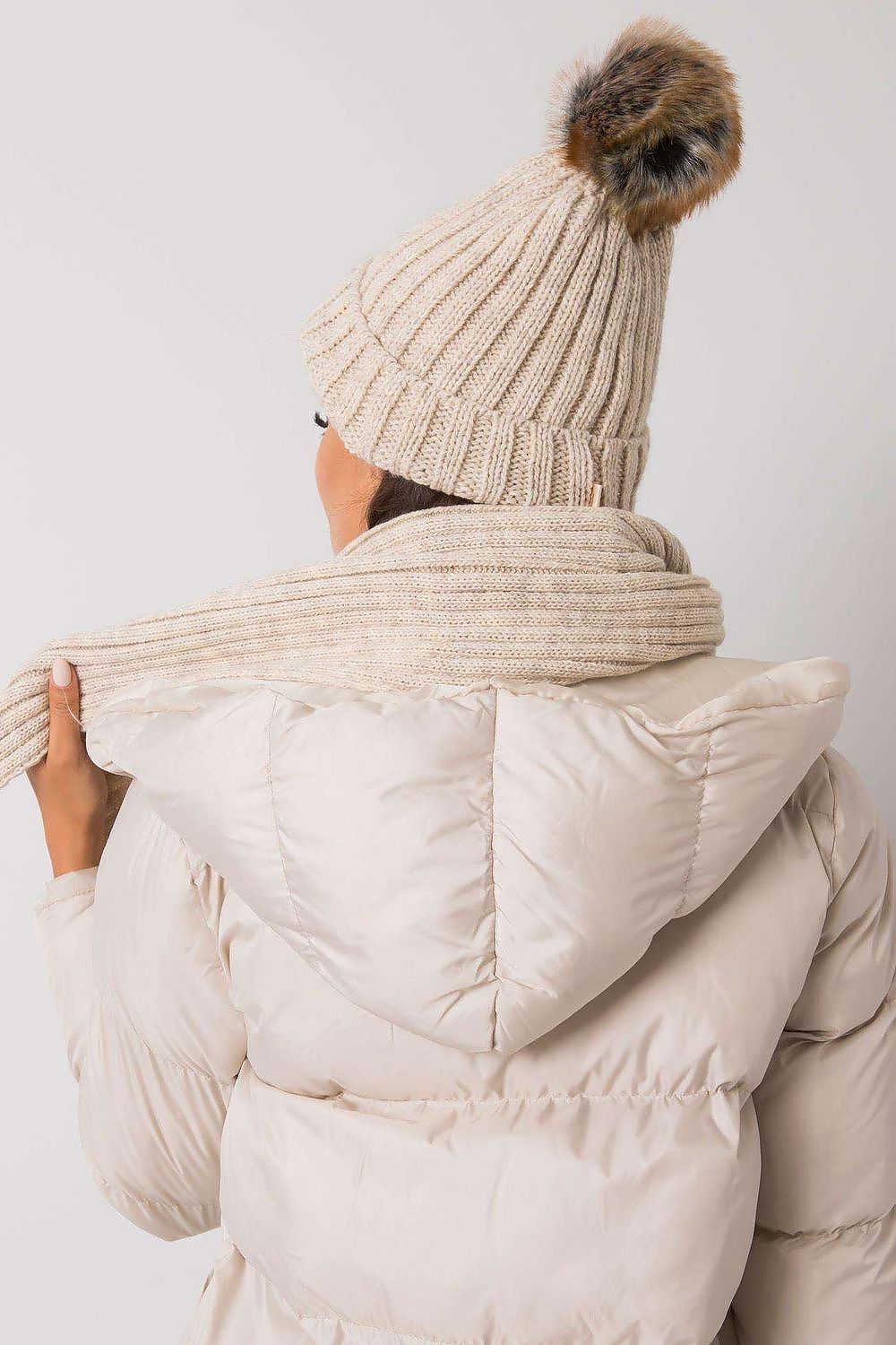 Chic winter accessories featuring a stylish knitted hat and scarf set, showcasing a woman from behind, perfect for sophisticated winter outings.