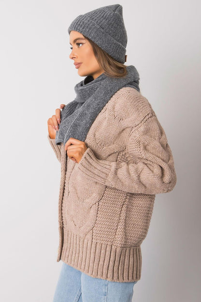 Profile view of a fashionable lady in a grey acrylic wool hat and matching scarf, complementing a stylish cable knit cardigan, perfect for cold weather outings.