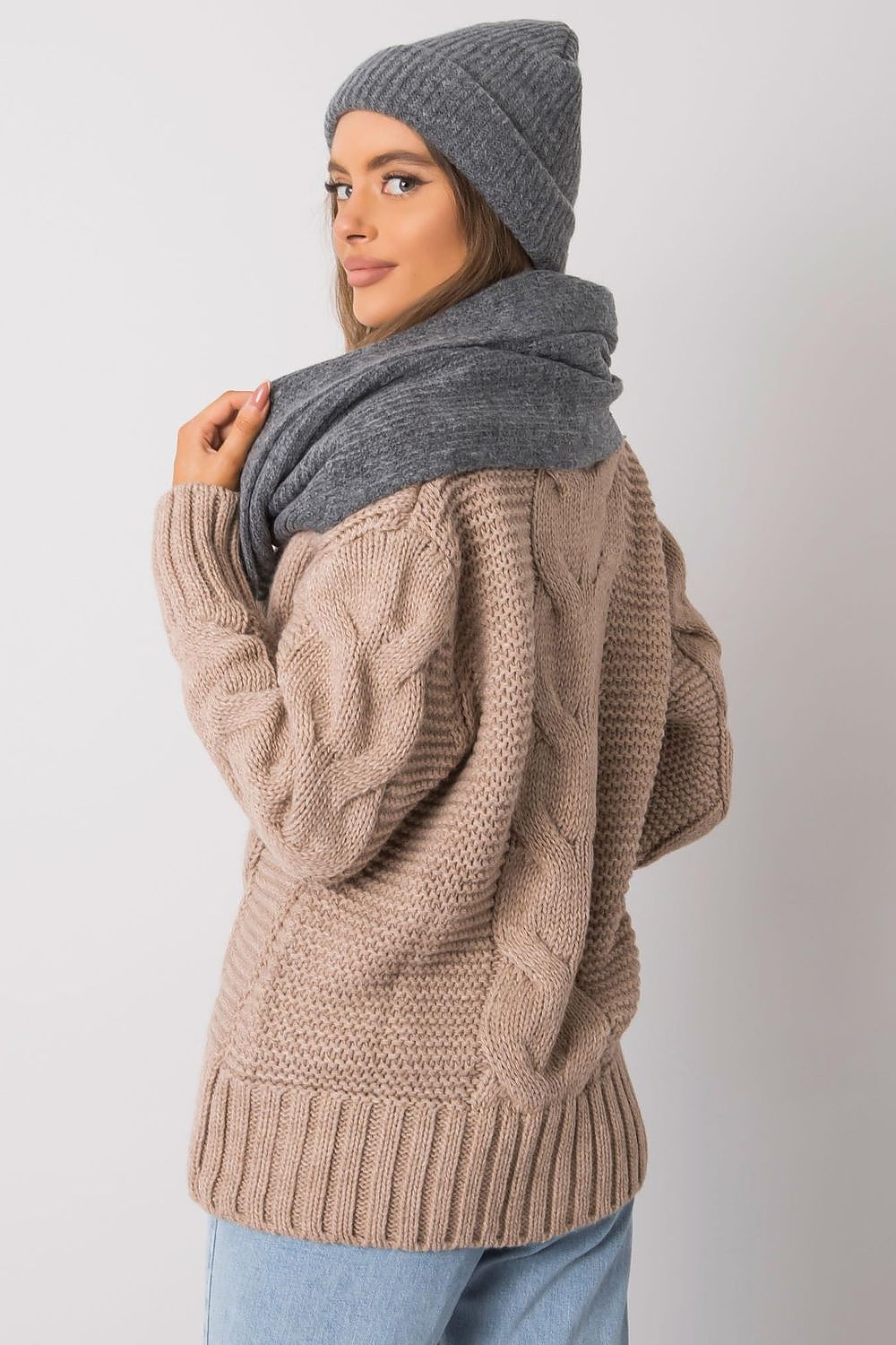 Stylish woman showcasing a warm grey winter hat and scarf combination, ideal for the sophisticated winter wardrobe, framed by a classic cable knit cardigan.