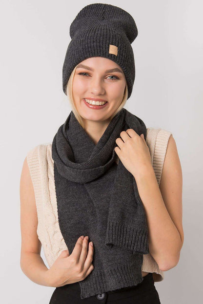Luxurious women's winter set featuring a stylish dark grey beanie hat and matching scarf, modelled by a woman with a bright smile, showcasing elegance and warmth.