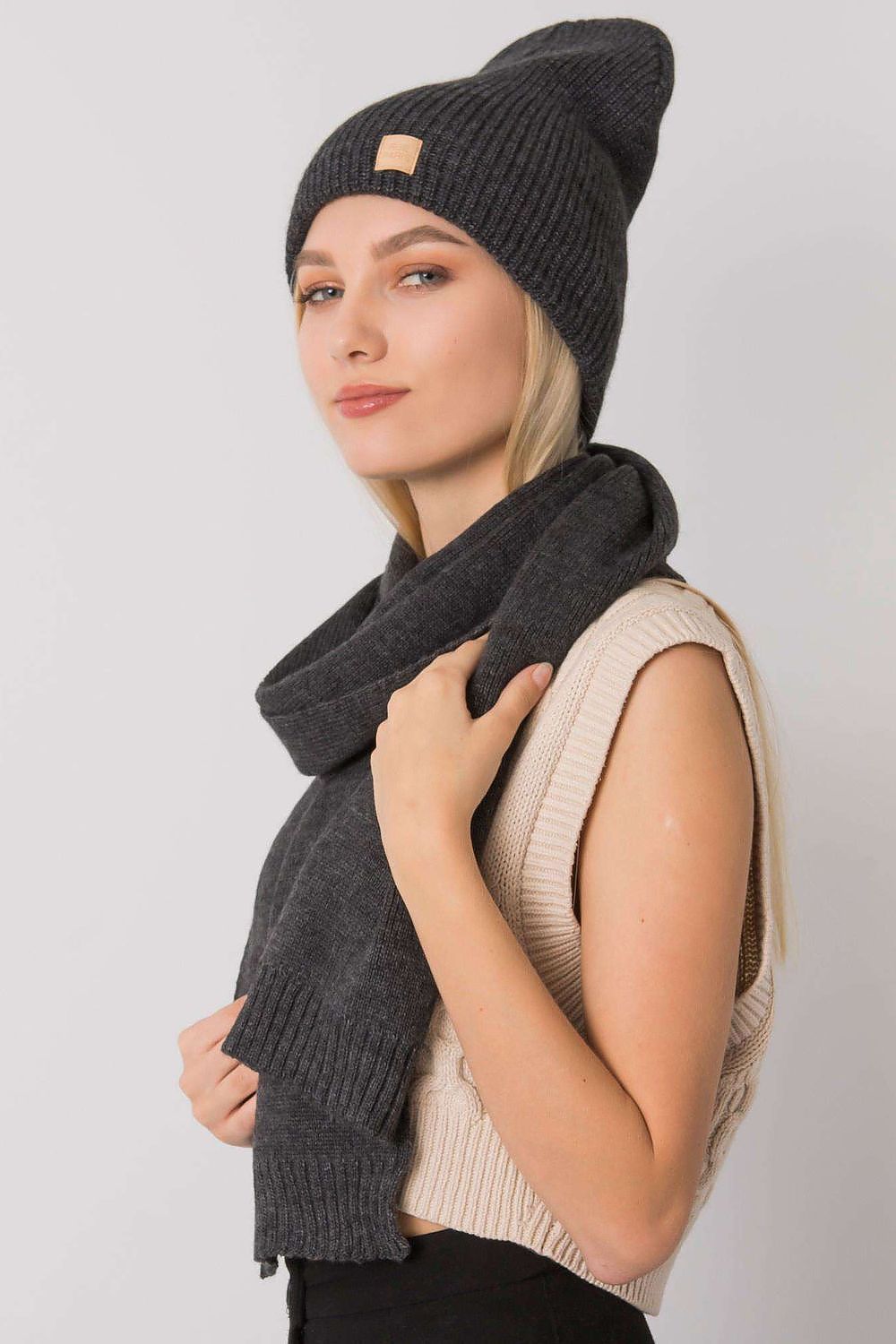 Chic women's winter outfit with a sophisticated dark grey beanie hat and matching scarf, highlighted by a confident model exuding style and comfort.