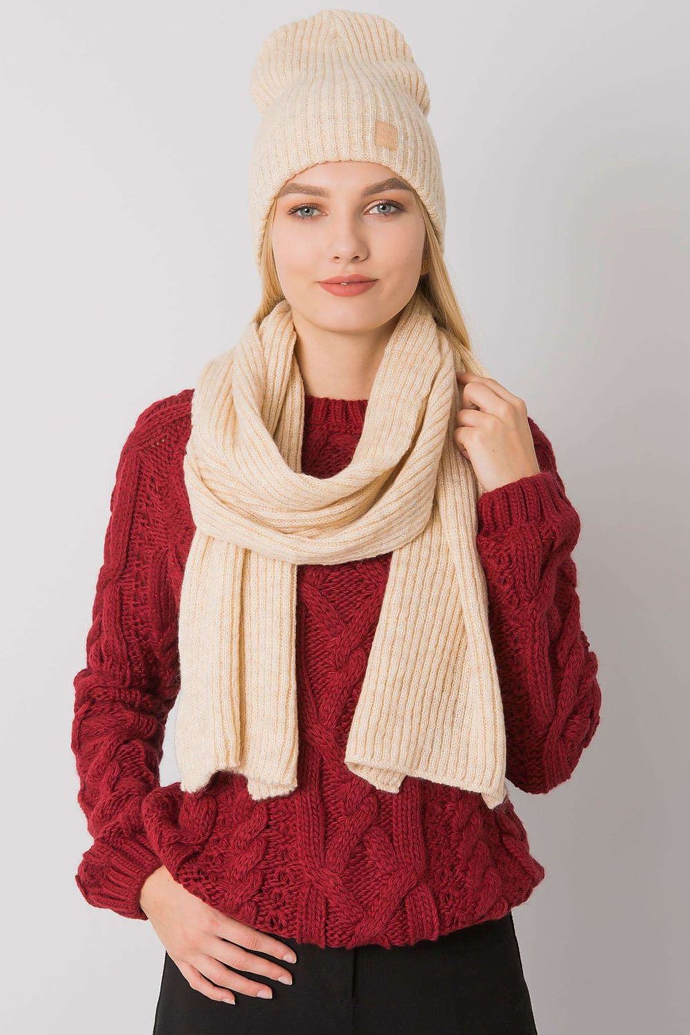 Elegant cream acrylic winter hat and scarf set, modelled with a deep red knitted sweater, perfect for cold weather fashion.