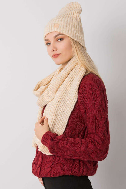 Chic side profile of a model wearing a cream winter hat and scarf set, complemented by a stylish red cable knit jumper.