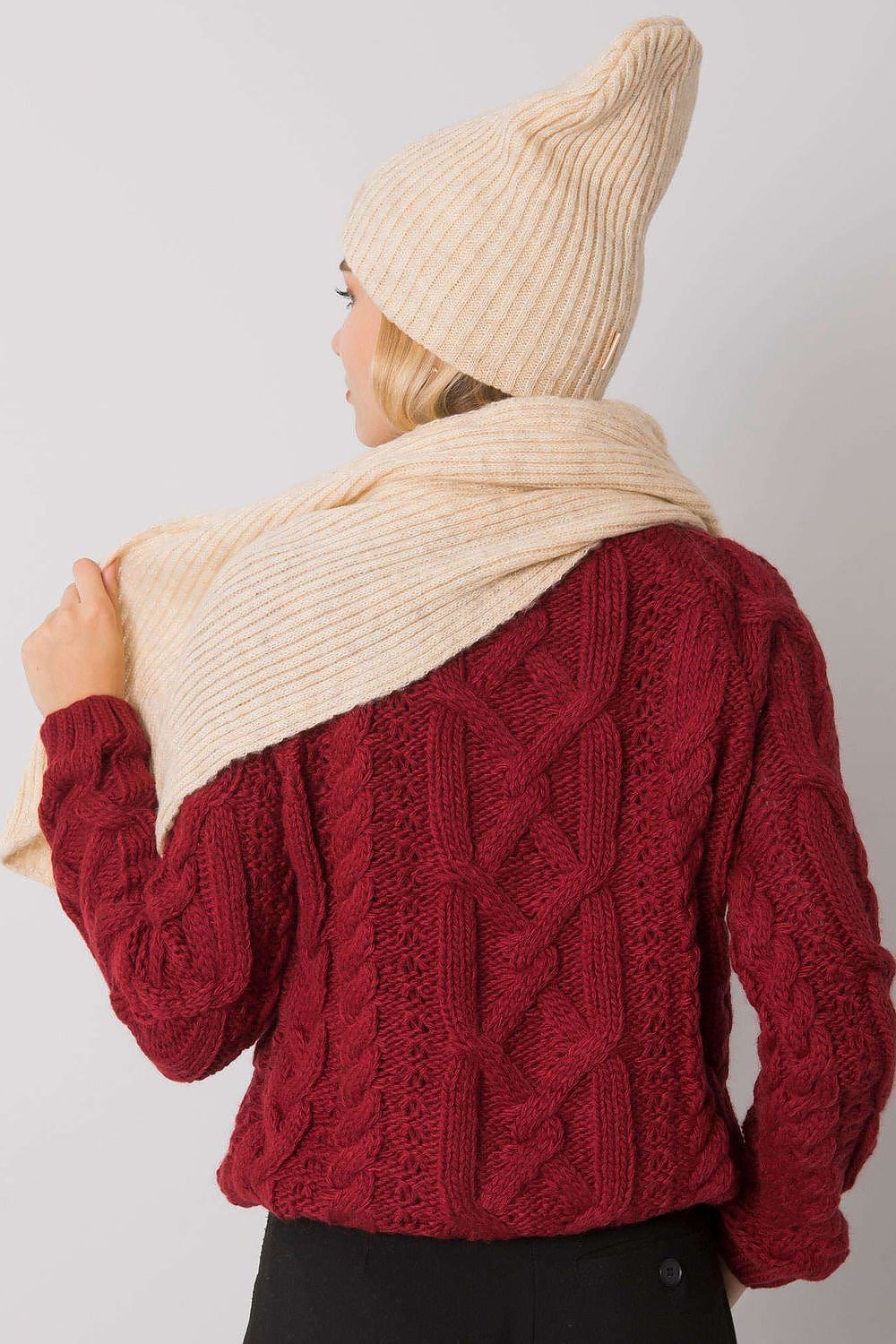 Rear view of a model showcasing the refined cream acrylic winter scarf draped elegantly under a matching beanie.