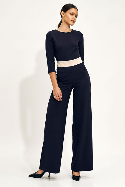 Chic navy blue jumpsuit featuring a fitted bodice and voluminous wide-leg trousers, model poses gracefully highlighting the design's elegance.