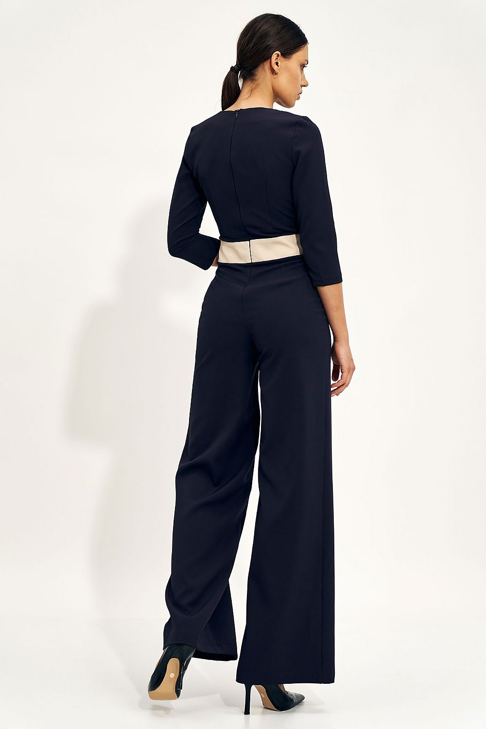 Back view of a luxurious navy blue jumpsuit with a fitted top and statement wide legs, accentuated with a decorative belt at the waist.