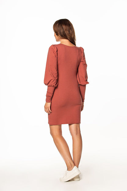 Back view of the luxurious Tessita mini knitted dress, showcasing the boat neckline and stylish long buffet sleeves, complemented by a minimalist background.