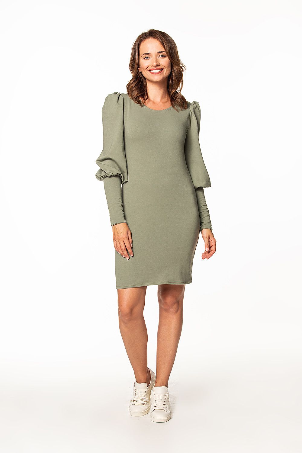 Chic lifestyle shot of a woman in a luxury knitted mini dress by Tessita, in a stylish olive green colour, featuring puffed sleeves and a flattering fit.