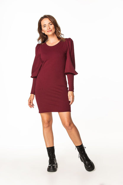 Stylish woman in a luxurious burgundy knitted mini dress with boat neckline and puffy sleeves by Tessita, showcasing a chic and contemporary design.