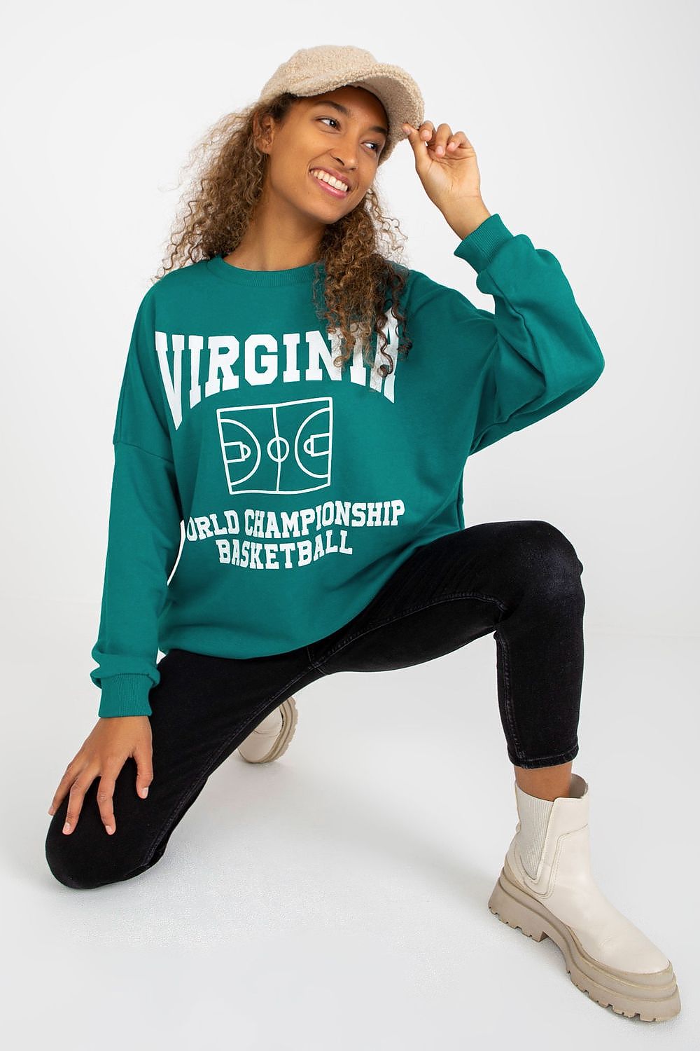 Luxury long-sleeved cotton sweatshirt in vibrant teal featuring decorative print and side pockets, styled with black skinny jeans and off-white ankle boots.