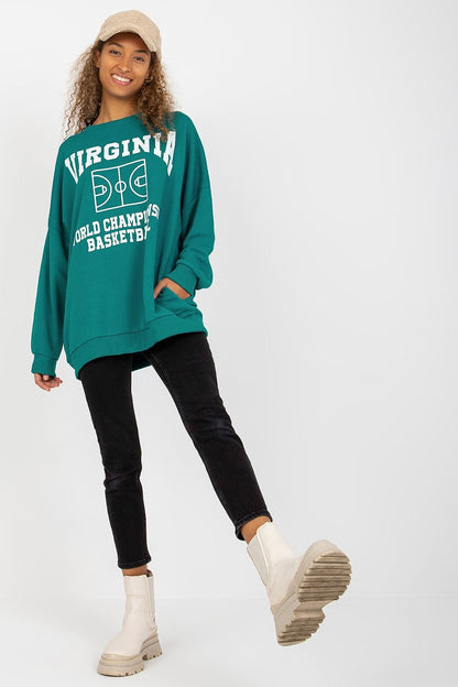 Fashionable long-sleeved sweatshirt in teal, adorned with a stylish basketball-themed print, paired elegantly with black jeans and chic ankle boots.