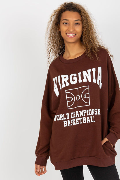 Luxury women's long-sleeved cotton sweatshirt in a rich brown hue, featuring a decorative print of basketball graphics and the word 'VIRGINIA.' Model showcases a comfortable and elegant oversized fit, perfect for casual styling with side pockets.