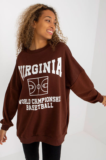 Chic women's long-sleeved cotton sweatshirt in stunning brown, adorned with a bold basketball-themed print stating 'WORLD CHAMPIONSHIP BASKETBALL.' Model poses gracefully, highlighting the stylish and relaxed oversized silhouette with practical side pockets.