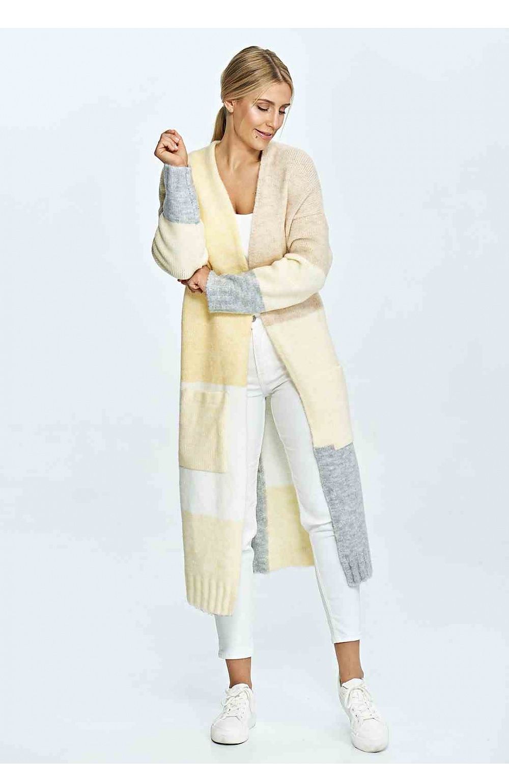 Elegant woman wearing a luxury acrylic blend cardigan in soft beige and cream tones, styled with white trousers and white sneakers, exuding sophistication and comfort.