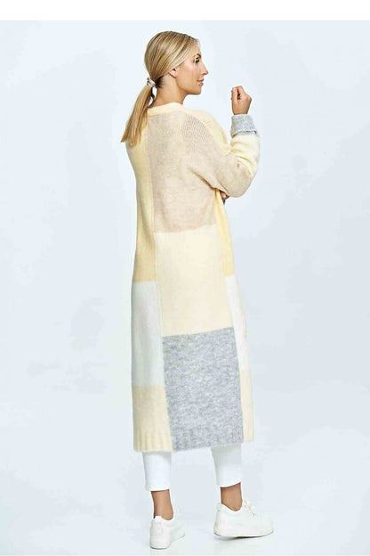 Chic rear view of a woman in a luxury knitted cardigan, displaying a soft colour palette of yellow and grey, paired elegantly with white pants, showcasing a modern and sophisticated look.