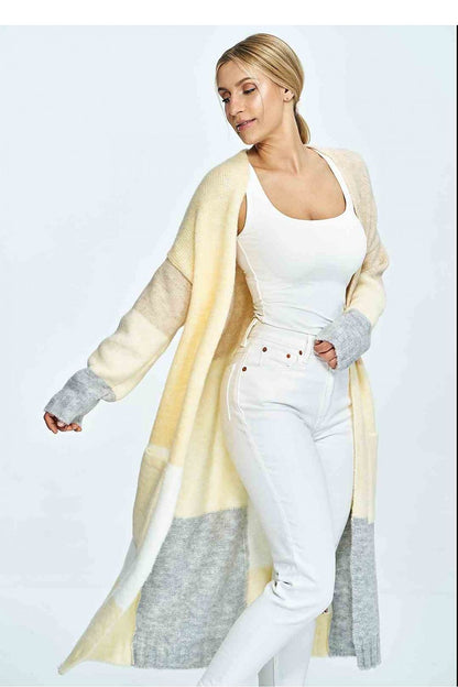 Stylish woman showcasing a luxury cream and grey Figl cardigan, paired with white trousers, exuding elegance with soft wool touch.