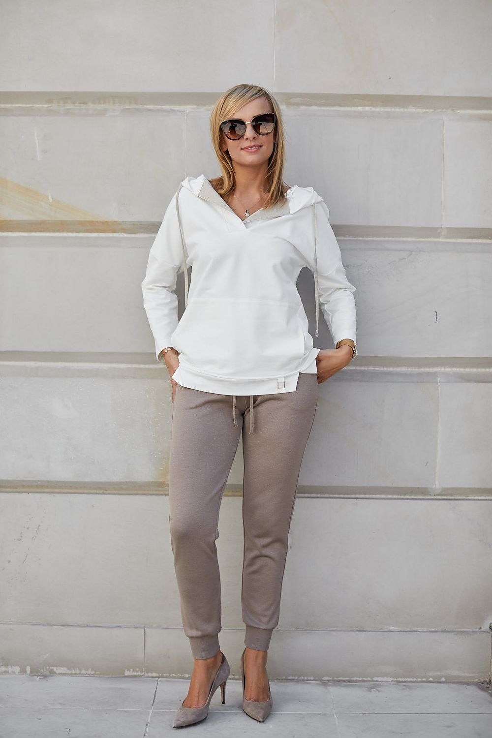Chic women's outfit featuring luxurious viscose stretch trousers paired with a sophisticated white hoodie, accentuated by elegant high-heeled shoes, exemplifying a blend of sporty and elegant fashion.