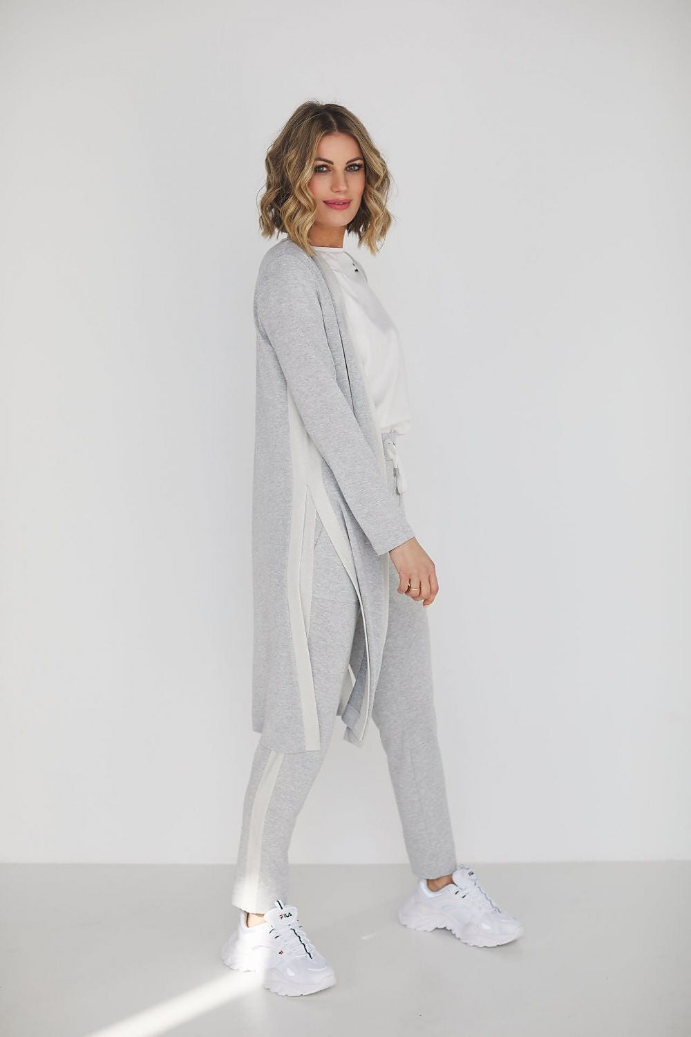 Elegant grey viscose set featuring high waist pants and a loose blouse, modelled by a stylish woman against a minimalist backdrop.