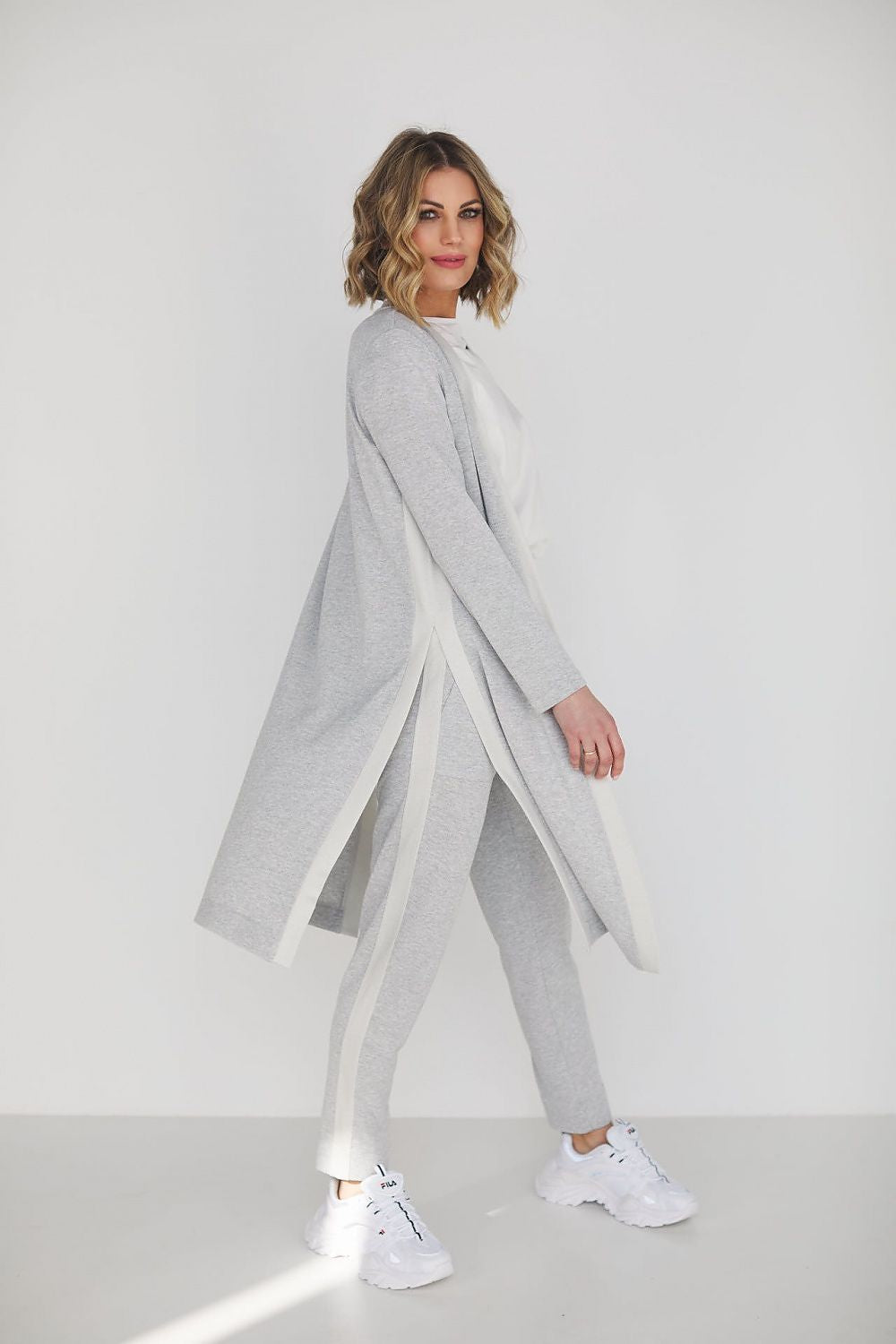 Chic grey high waist pants and blouse ensemble displayed by a fashionable woman, showcasing comfort and sophistication in a sleek environment.